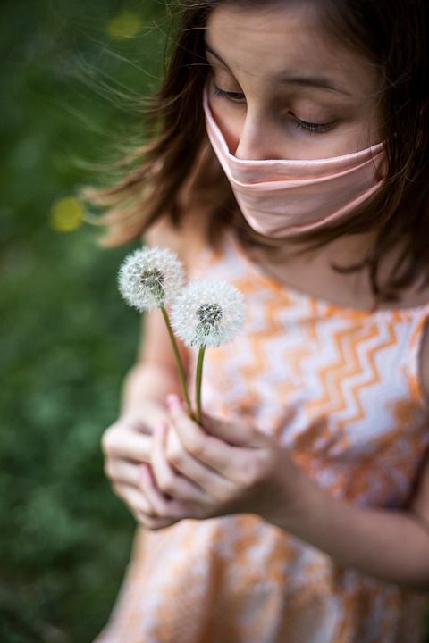 girl in mask holding dandelion