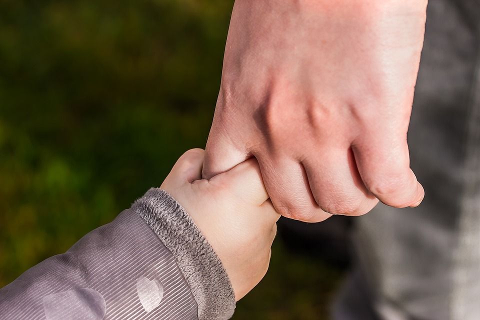 Child holding hands with adult