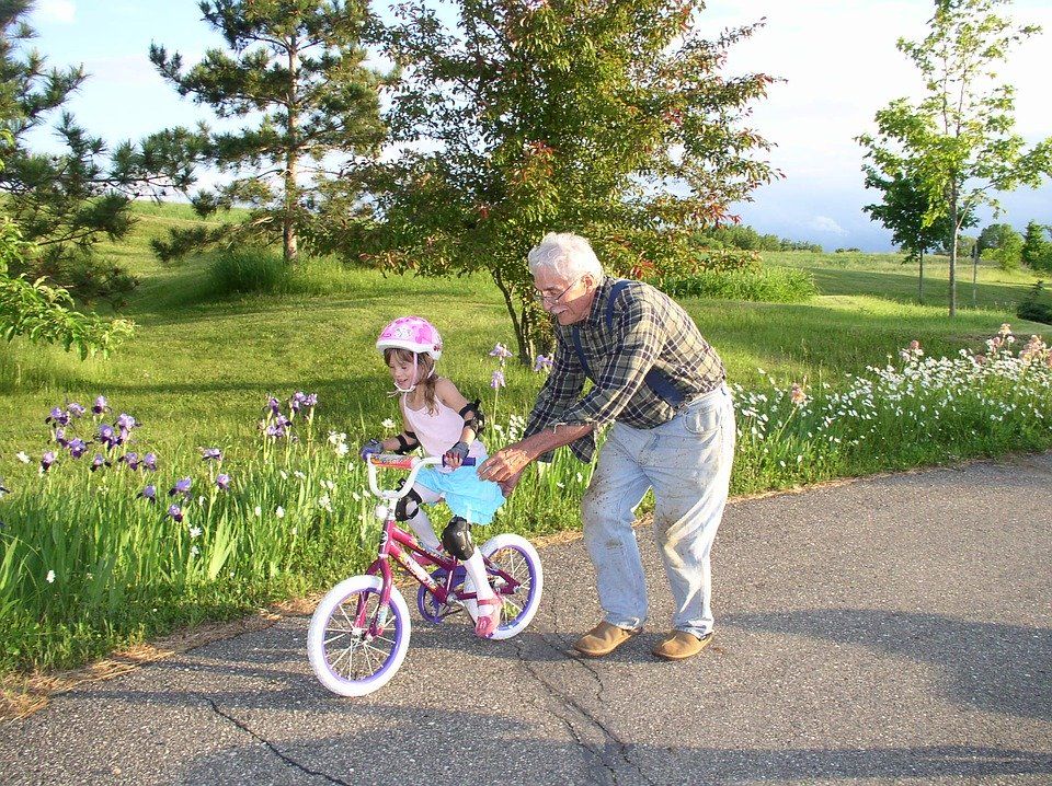 grandpa pushing granddaughter on bike
